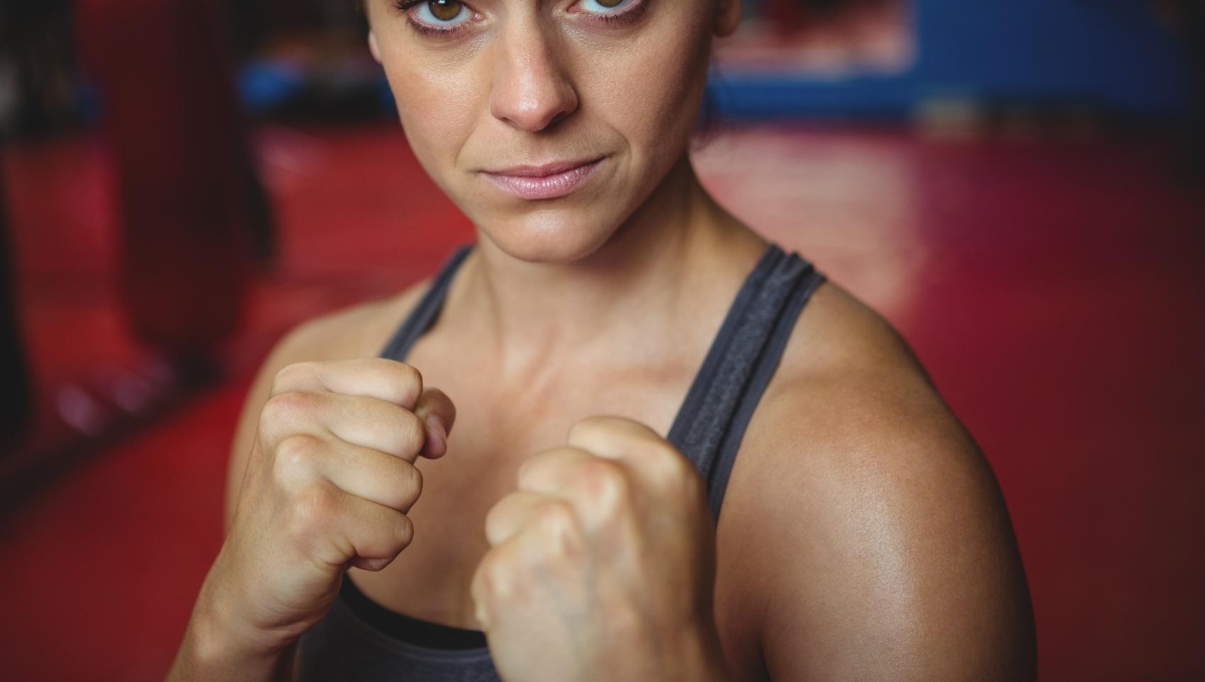 zuversichtlich-weiblicher-boxer-der-boxhaltung-durchfuhrt